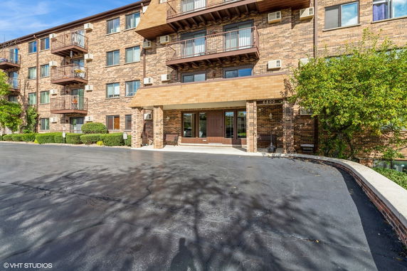 Front view of a multi-story brick apartment building with balconies and a main entrance.