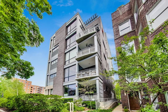 Front view of a multi-story residential building with balconies and large windows.