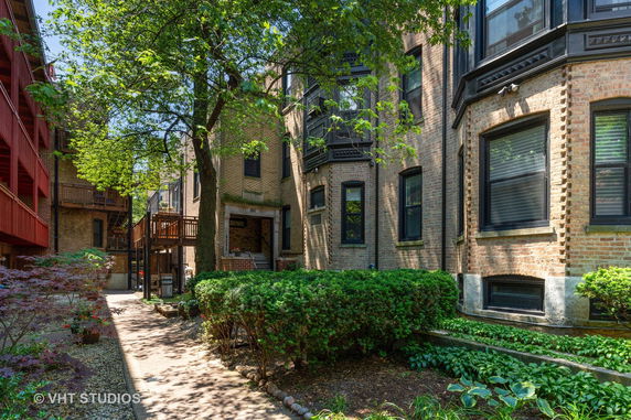 Front view of a multi-story brick building with large windows and surrounding greenery.