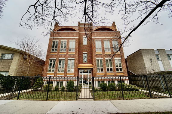 Front view of a three-story brick building with multiple windows and a gated entrance.