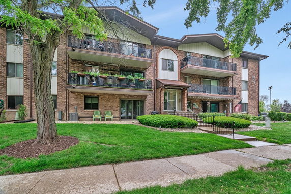 Front view of a multi-story brick apartment building with balconies.
