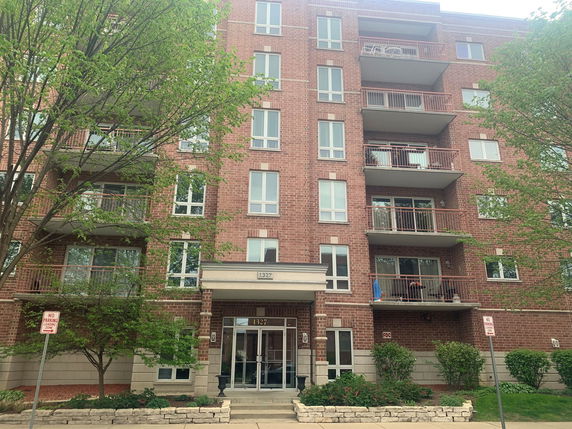 Front view of a multi-story brick apartment building with balconies.