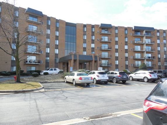 Front view of a multi-story residential building with parking area.