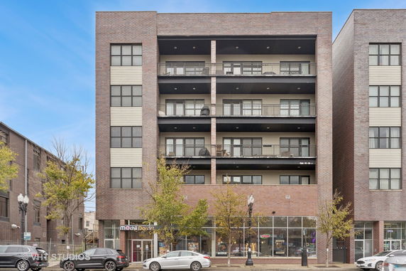 Front view of a multi-story commercial and residential building with a brick facade and balconies.