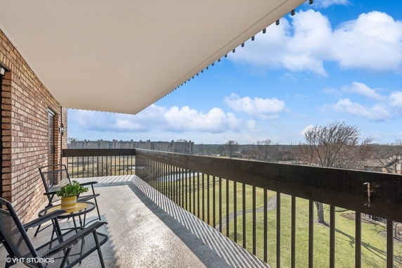 Spacious balcony with seating offering a panoramic view of the surrounding area.