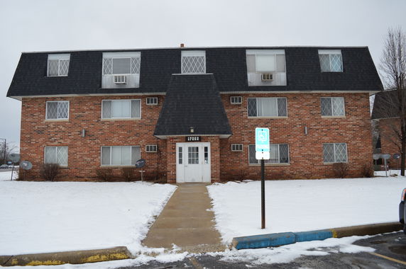 Front view of a multi-story brick apartment building with a prominent central entrance.