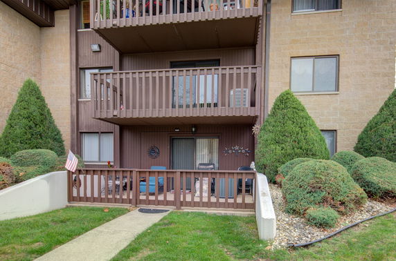 Front view of a multi-story building with balconies and a small garden area.