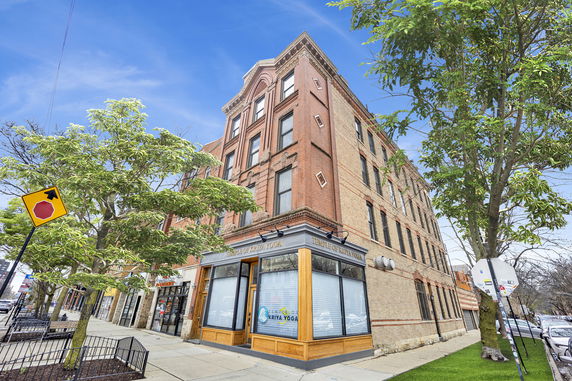 Front view of a multi-story brick building with large windows.