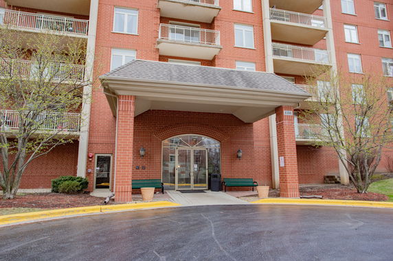 Front view of a multi-story brick building with balconies and a covered entrance.