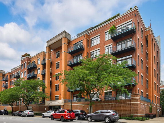 Front view of a multi-story brick apartment building with balconies.
