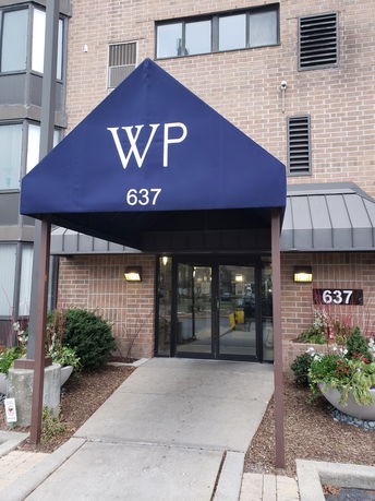 Front view of a building entrance with a blue canopy and brick facade.