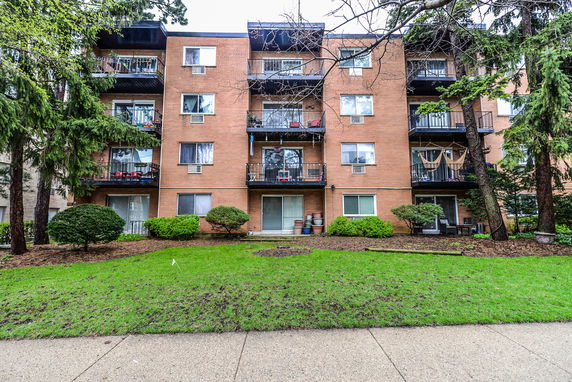Front view of a multi-story brick apartment building with balconies.