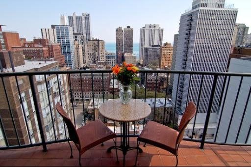 Panoramic view of a cityscape from a balcony with chairs and a table.