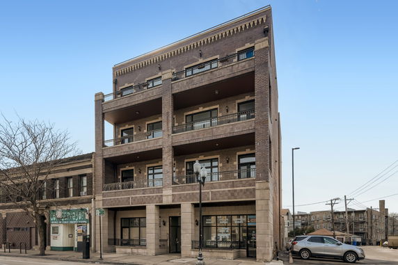 Front view of a three-story brick building with balconies.