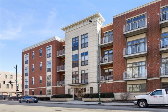 Front view of a multi-story brick apartment building with balconies.