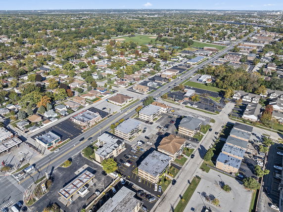 Aerial view of a suburban area with roads, buildings, and green spaces.