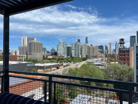 Panoramic view of a city skyline from a balcony with various skyscrapers and a water tower.