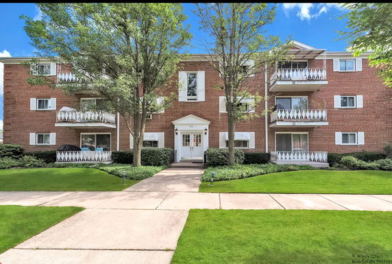 Front view of a multi-story brick apartment building with balconies.