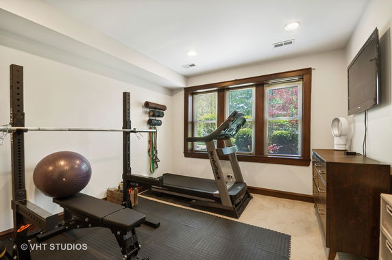 Indoor gym area with exercise equipment including a treadmill and weight bench.
