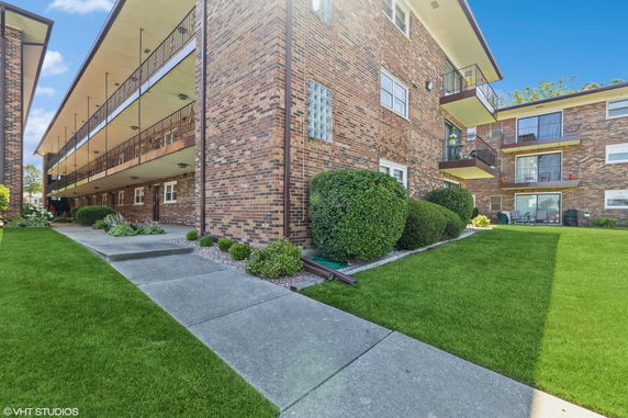 Corner view of a multi-story brick apartment building with balconies.