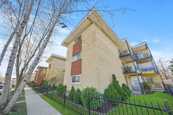 Front view of a multi-story apartment building with balconies and brick exterior.