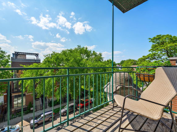 Balcony view overlooking a street lined with trees and buildings.