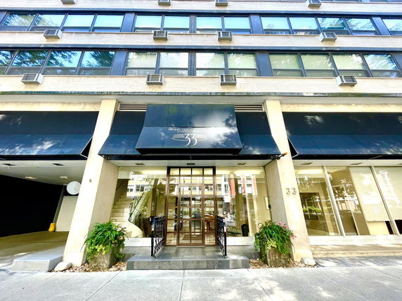 Front view of a multi-story building with large windows and an entrance canopy.
