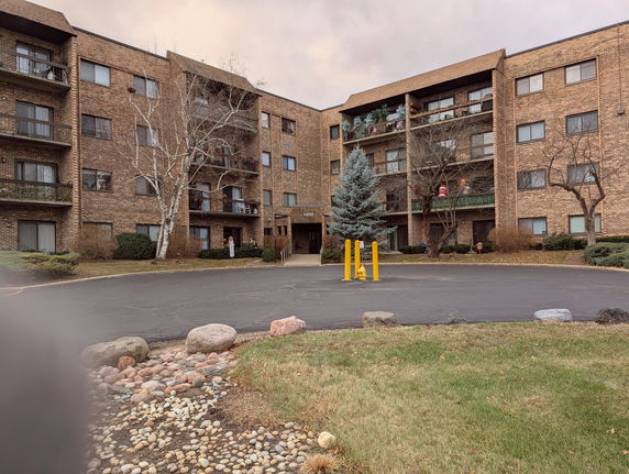 Front view of a multi-story apartment building with balconies and a central entrance.