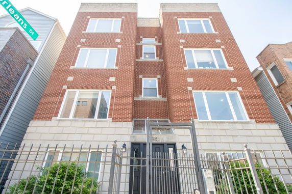 Front view of a multi-story brick building with large windows.