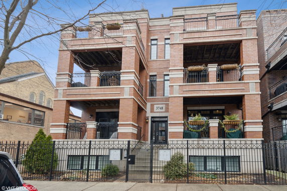 Front view of a multi-story brick apartment building with balconies.