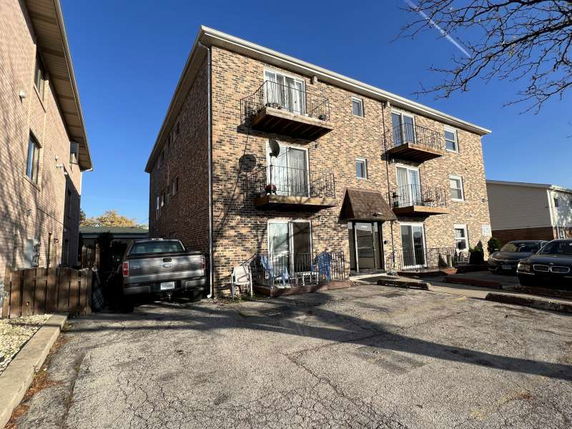 Front view of a three-story brick apartment building with small balconies.