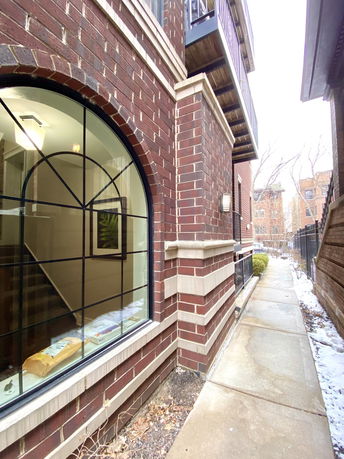 Side view of a brick building with large arched window and balconies.