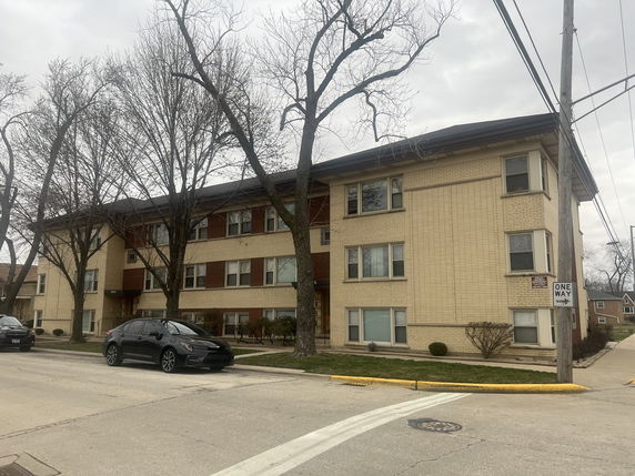 Front view of a three-story apartment building with a brick facade.