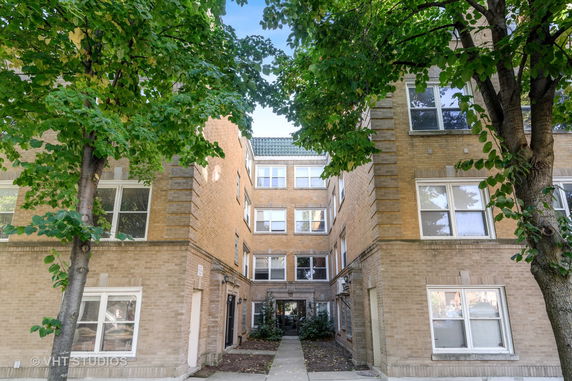 Front view of a brick apartment building with multiple floors and central entrance.