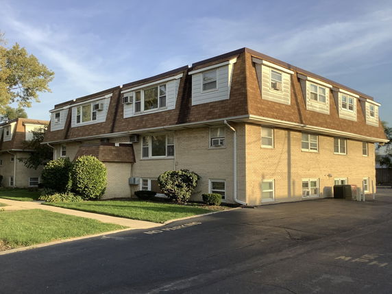 Front view of a two-story apartment building with a brown mansard roof.