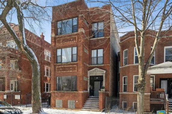 Front view of a three-story brick building with large windows.