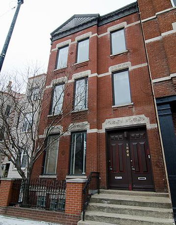 Front view of a three-story brick townhouse with decorative stone accents around the windows and entrance.