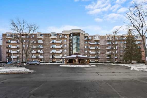 Front view of a multi-story apartment building with a covered entrance.