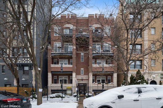 Front view of a multi-story brick apartment building with balconies.