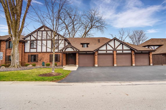 Front view of a multi-story house with a brick facade and three-car garage.
