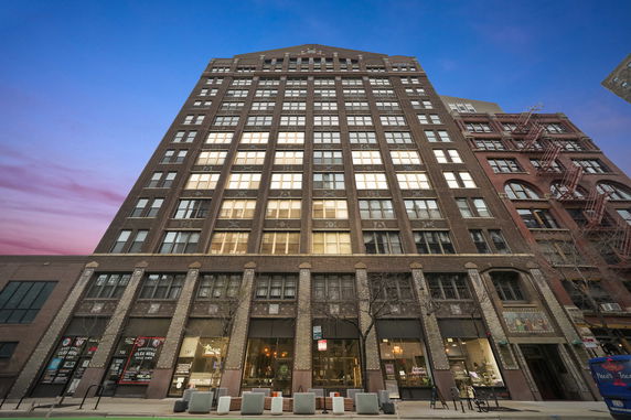 Front view of a tall brick building with large windows at dusk.