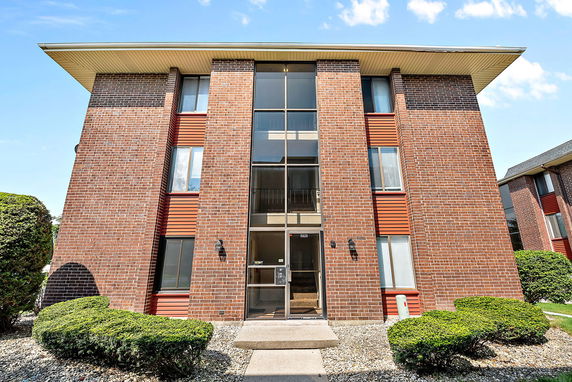 Front view of a three-story brick building with large windows.