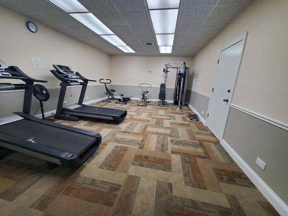 Room with gym equipment including treadmills and exercise machines.