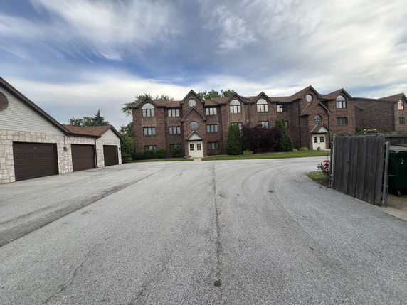 Front view of a large brick apartment building with multiple gables and a main entrance.