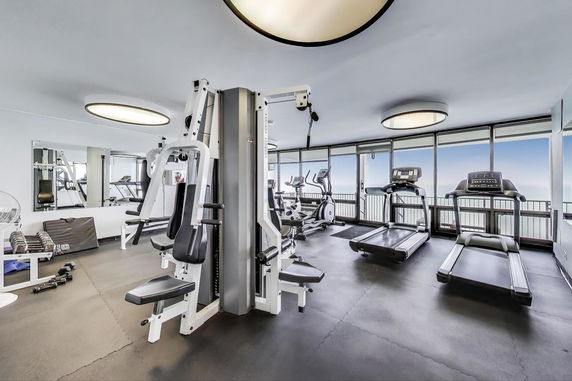 Gym area with exercise machines and large mirrors.