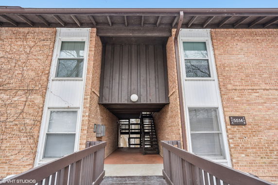 Front view of a multi-story brick building with wooden accents and an external staircase.