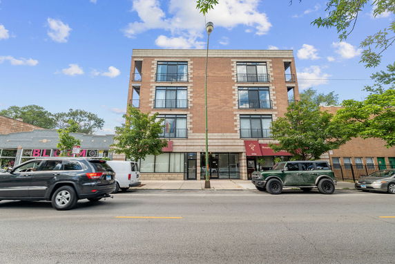 Front view of a multi-story brick building with balconies and a street-level commercial area.