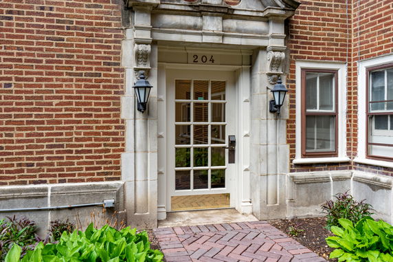 Front view of a brick building entrance with a decorative stone frame and glass door.