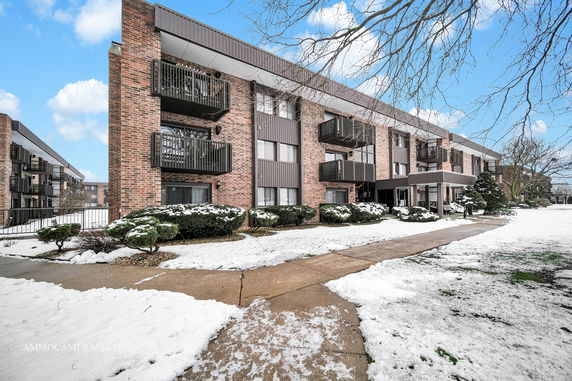 Front view of a multi-story brick apartment building with balconies.