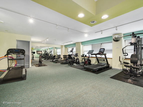 Room with gym equipment including treadmills and exercise machines.